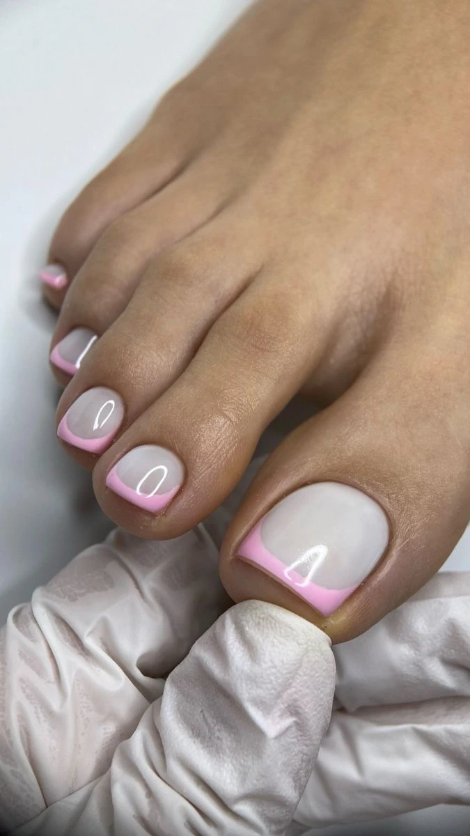 Pink French tip pedicure being finished by a nail technician