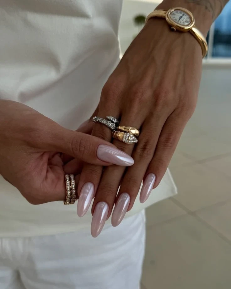 Pearl chrome almond nails with gold rings and a gold watch